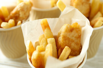 Paper cups with fried fish and chips, close up