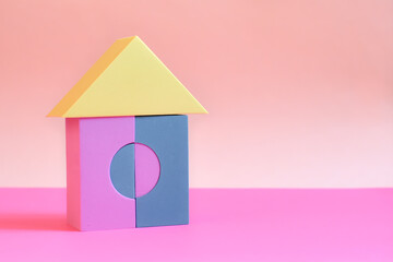 toy house built from building blocks for children on pink background. Colored cubes in shape of house. house made of building blocks. Concept: dream home, happy life, mortgage investment