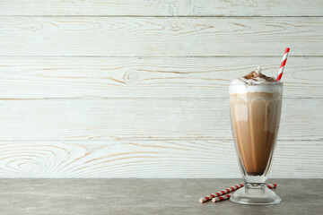 Glass of chocolate milkshake and straws on gray table