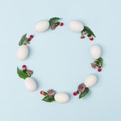 Creative copy space made of Easter eggs and flowers on bright blue background. Minimal holiday concept. Flat lay.