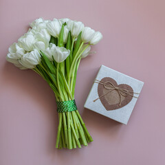 White tulips and gift box on pink background. Spring concept.