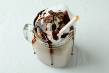Glass of chocolate milkshake on white textured table
