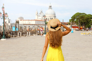 Fototapeta premium Tourism in Venice, Italy. Young traveler girl on summer holidays in Europe. Female back view with Venice landscape on the background.