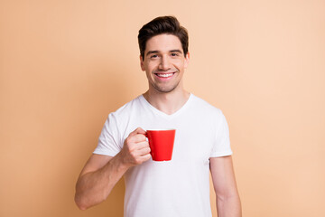 Portrait of satisfied young person smile arm holding coffee cup isolated on beige color background