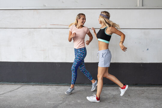Two young females jogging at the city street.