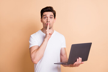 Portrait of worried handsome person finger covering lips do not talk isolated on beige color background - obrazy, fototapety, plakaty