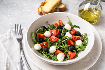 Typical dishes of the Mediterranean diet : mozzarella balls, black olives, olive oil, salad with tomatoes and arugula, bruschetta. Healthy Food Italian cuisine. 