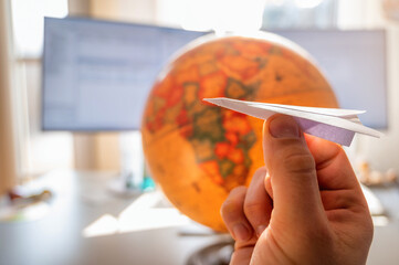Bei der Arbeit an den nächsten Urlaub denken dargestellt mit einem Papierflugzeug und einem Globus auf einem Schreibtisch