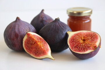 Fresh ripened purple figs. Creative composition a decorative banner of whole and sliced exotic fruit and fig jam isolated on white table background.Food photography.