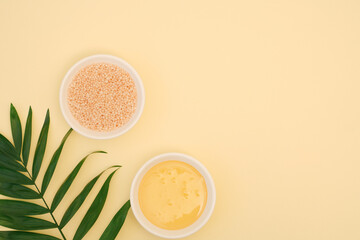 Beautiful minimalistic spa background with pearl shaped sea bath salt, natural flower honey and green fresh leaf. Body beauty concept on yellow background with copy space, top view, flat lay