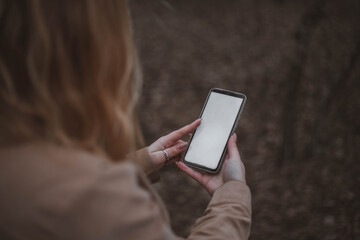 Smartphone mockup. Girl in the forest holding a phone with a white screen