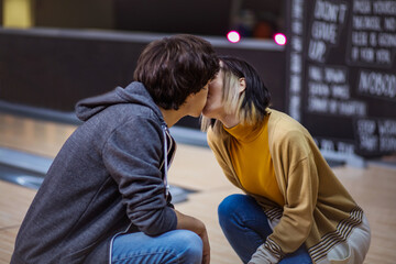 Couple kissing in a bowling alley.