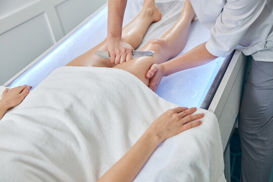 Masseuse performing therapeutic massage with metal tool
