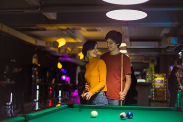 Young couple spending time in billiard room. Time for competition. Couple talking.