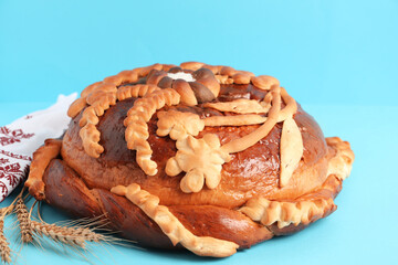 Rushnyk with korovai on light blue background, closeup. Ukrainian bread and salt welcoming tradition