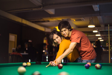 Boyfriend teaching his girlfriend to playing billiard.