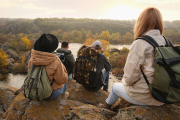 Group of friends with backpacks near mountain river, back view