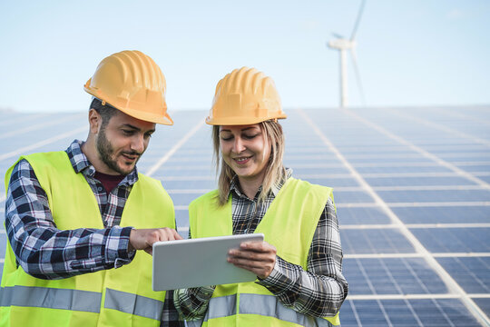 Young people working with digital tablet at renewable energy farm - Focus on faces