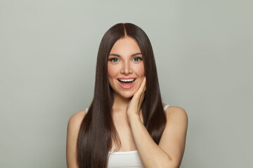 Beautiful young surprised brunette model woman with clear skin and long healthy straight hair on...