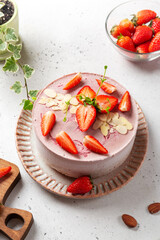 Delicious raw vegan cake with strawberries, decorated with berries and almond petals, gluten-free,...