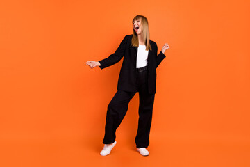 Full length body size view of attractive cheerful dreamy girl dancing singing having fun isolated over bright orange color background
