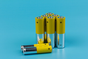 Photo of gray-yellow alkaline AA batteries on blue background. Recycling of rechargeable NiMH...