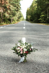 wedding bouquet stands in the middle of the road in the forest