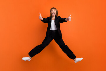 Fototapeta na wymiar Full size photo of happy excited crazy good mood funky girl jumping showing you thumb-up isolated on orange color background