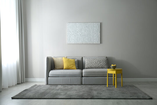 Stylish living room with sofa. Interior design in grey and yellow colors