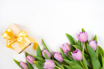 Tulips and gift box on a white background. Festive floral concept with clean text space. Flat lay. View from above.