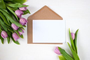 Tulips envelope with a white sheet of paper. Festive floral concept with clean text space. Flat lay. View from above.
