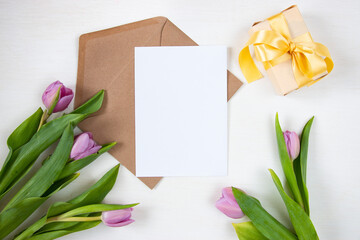 Tulips envelope with a white sheet of paper. Festive floral concept with clean text space. Flat lay. View from above.