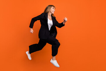 Fototapeta na wymiar Full size profile side photo of young beautiful charming girl look copyspace running fast in air isolated on orange color background