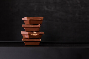 Pieces of milk chocolate were stacked on top of each other. Dark blurred background