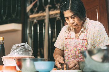 Aunthentic portrait of happy asian elderly woman cooking for family at local traditional kitchen style at home.