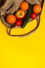 Fruits and vegetables in a grocery bag on the yellow background, flat lay, top view, copy space. Healthy lifestyle concept, healthy food. Trend color of the year 2021, vertical image