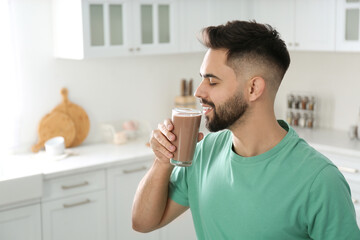 Young man drinking chocolate milk in kitchen - Powered by Adobe