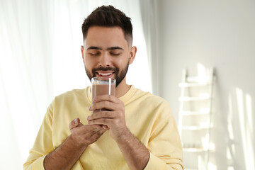 Young man drinking chocolate milk in room