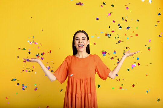 Emotional Woman And Falling Confetti On Yellow Background