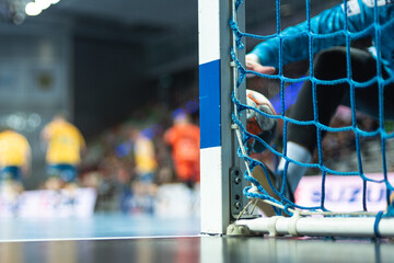 Detail of handball goal post with net and handball match in the background. - obrazy, fototapety, plakaty