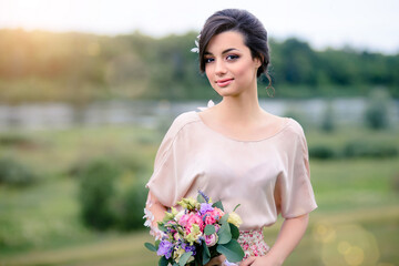 Gentle young woman with beautiful bouquet enjoys a summer day at sunset