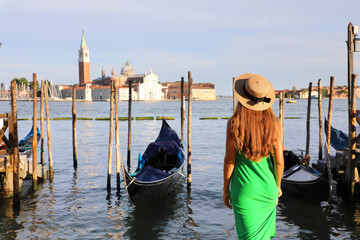 Fototapeta na wymiar Romantic sunset in Venice, Italy. Back view of young woman admiring Venetian Lagoon.