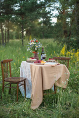 summer picnic in nature set table with flowers and wine