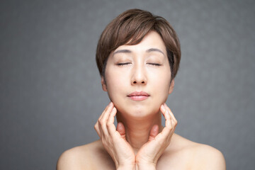 Obraz na płótnie Canvas 目をつぶって顎に手を当てる中年の日本人女性