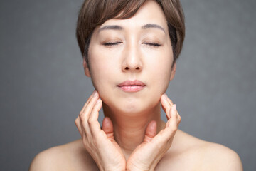 Obraz na płótnie Canvas 目をつぶって顎に手を当てる中年の日本人女性