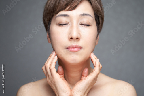 目をつぶって顎に手を当てる中年の日本人女性 Wall Mural Mapo