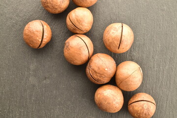 Several ripe brown macadamia nuts on a slate serving board, close-up.