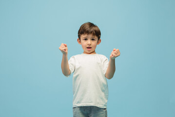 Winner. Happy, smiley little caucasian boy isolated on blue studio background with copyspace for ad. Looks happy, cheerful. Childhood, education, human emotions, facial expression concept.