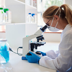 Female technician looking at lab samples in a microscope