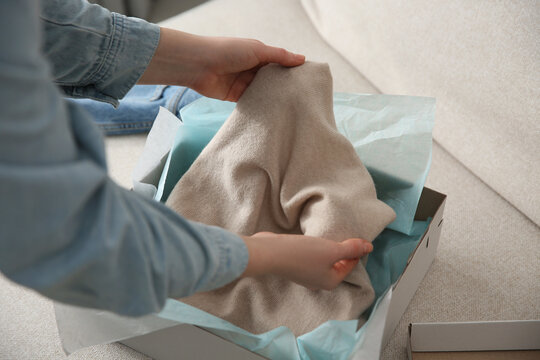 Woman Taking Soft Cashmere Sweater Out Of Box Indoors, Closeup